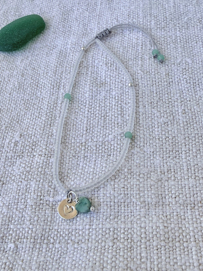 Bracelet Brume en entier, perles cristal mat, angélites vertes et médaille cœur en argent 925, posé sur du lin avec un verre de mer — fait main en Normandie
