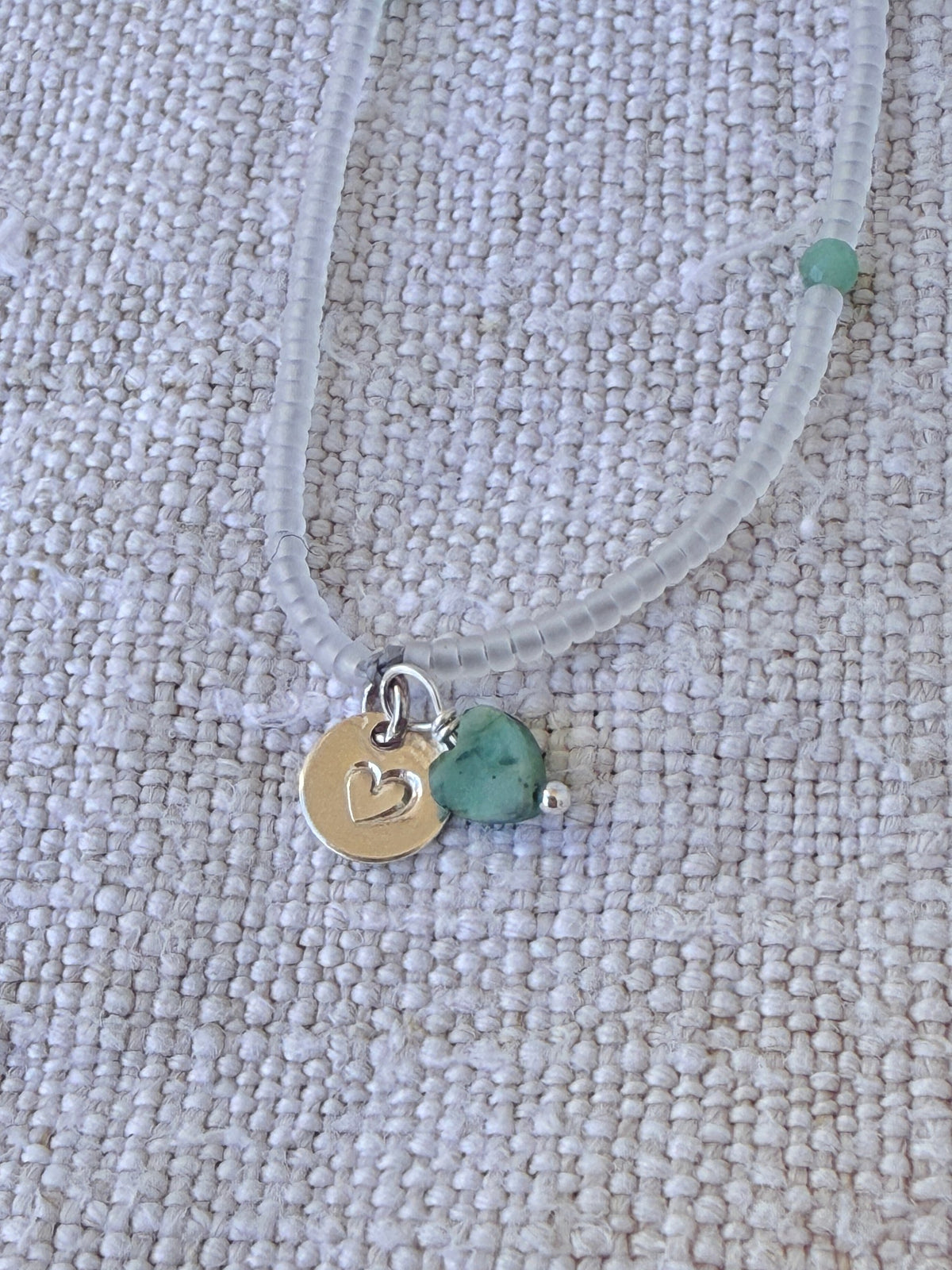 Détail du bracelet Brume : médaille cœur en argent 925 et cœur en pierre verte sur perles cristal mat