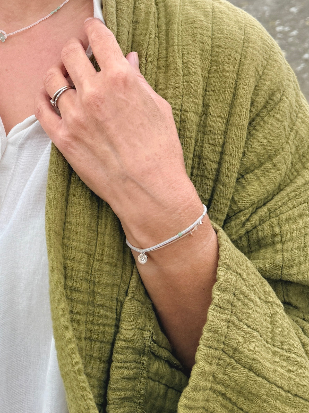 Bracelet Brume porté au poignet, médaille ronde en argent 925 poinçonnée d'un cœur et angélite verte
