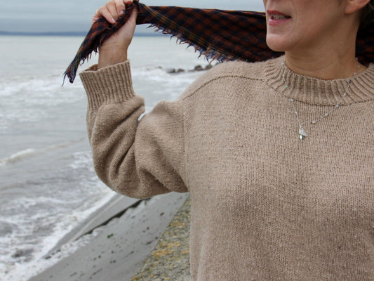 Collier long Brume en pierre de lune et argent 925, porté sur un pull beige au bord de la mer
