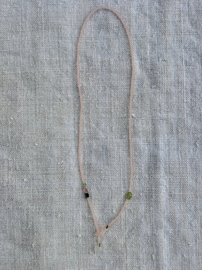 Collier lasso Bruyère en entier, perles rose poudré mat, tourmalines et verre dépoli, posé sur du lin — fait main en Normandie