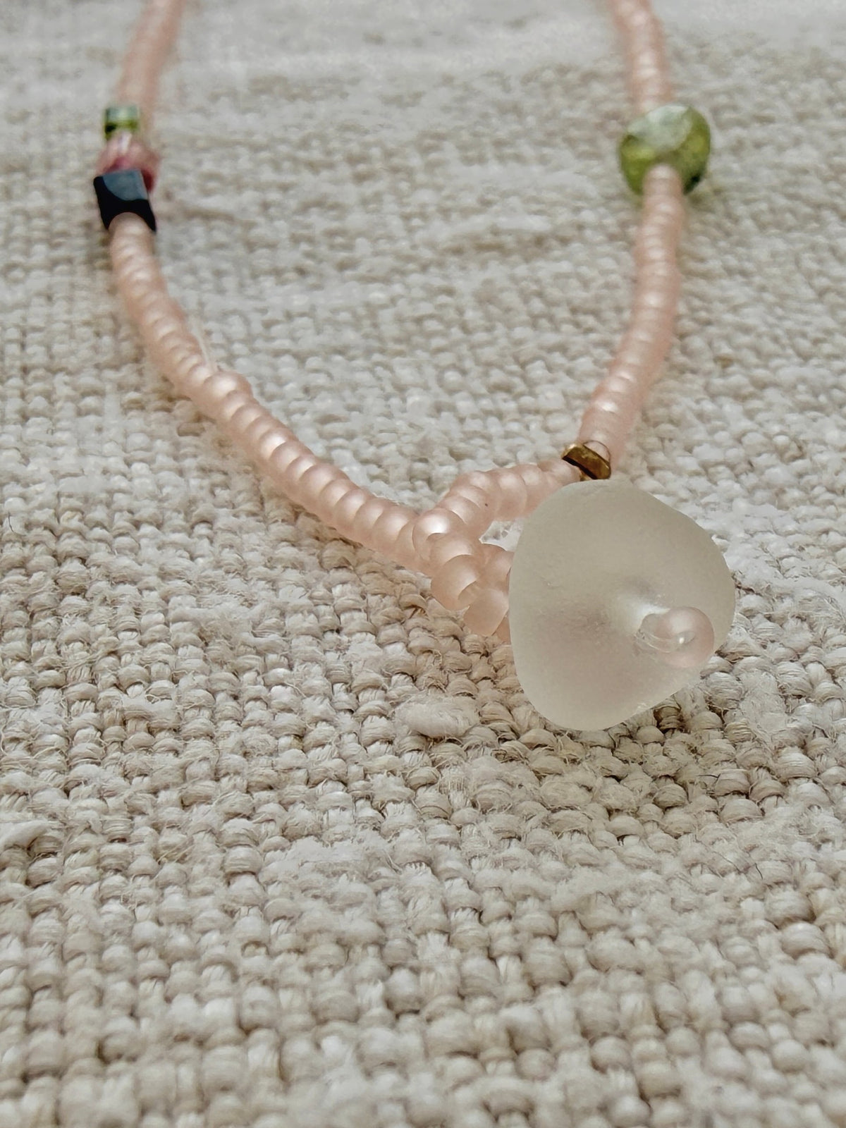 Gros plan sur la perle de verre dépoli qui ferme le collier lasso Bruyère