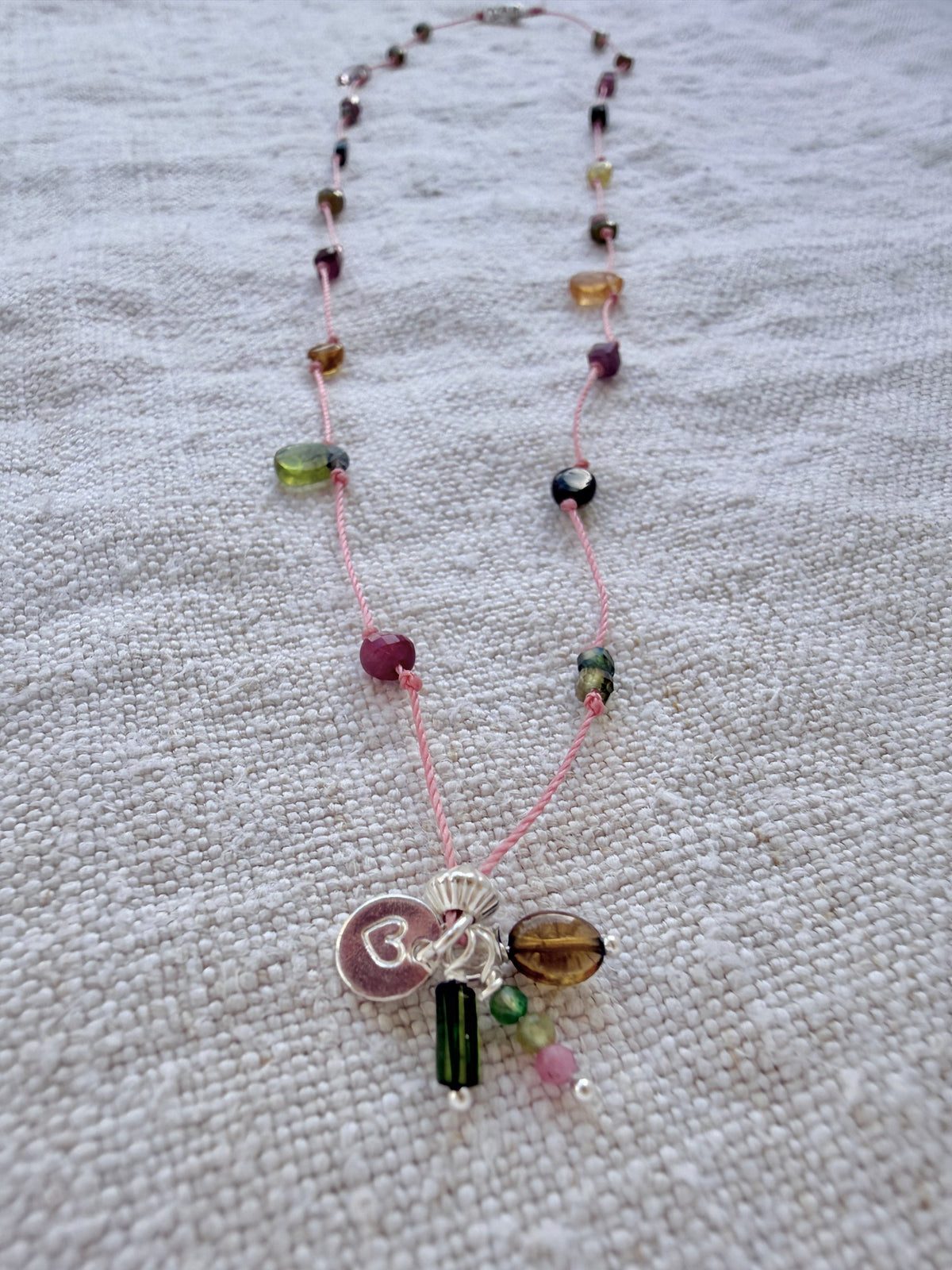Collier long Bruyère posé sur du lin, tourmalines roses, vertes et miel et grappe de pampilles argent