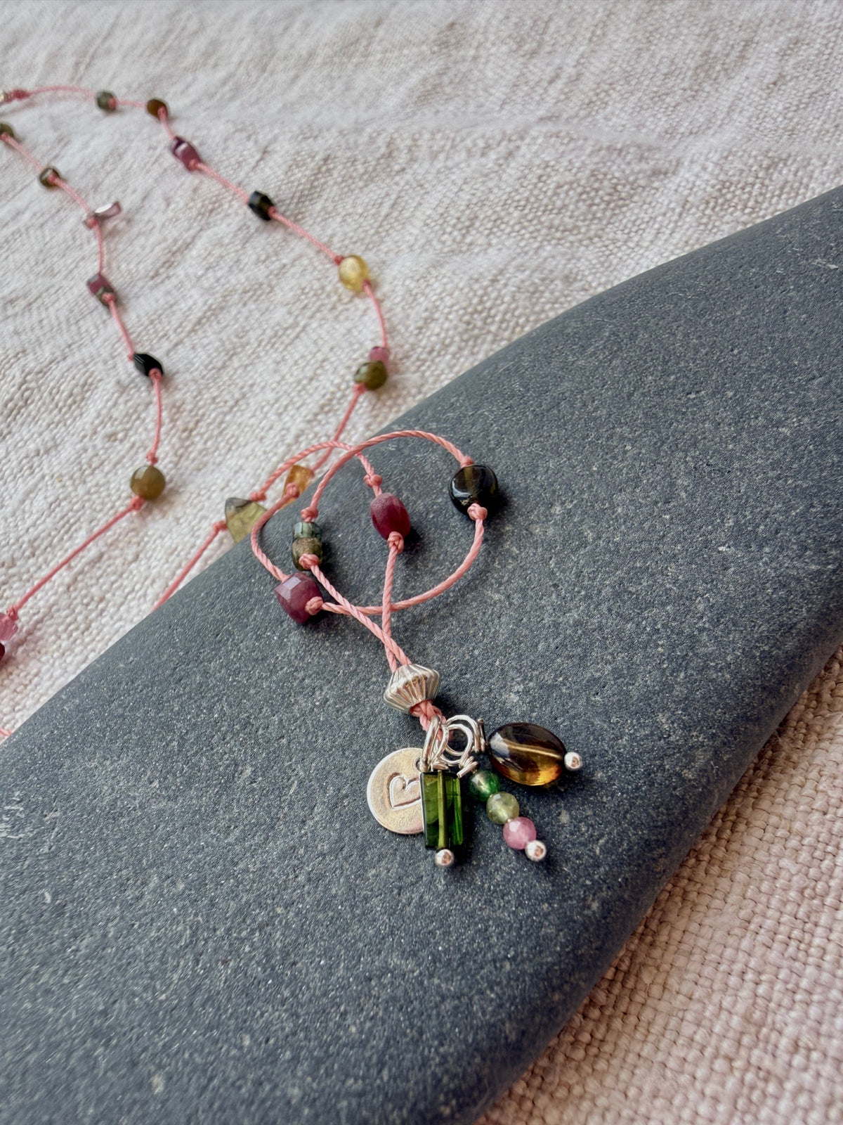Grappe de pampilles du collier Bruyère sur un galet : médaille cœur argent poinçonnée et tourmalines
