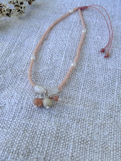 Bracelet Dune posé sur du lin près de fleurs séchées, perles rose poudré, nacre et grappe de rhodochrosite