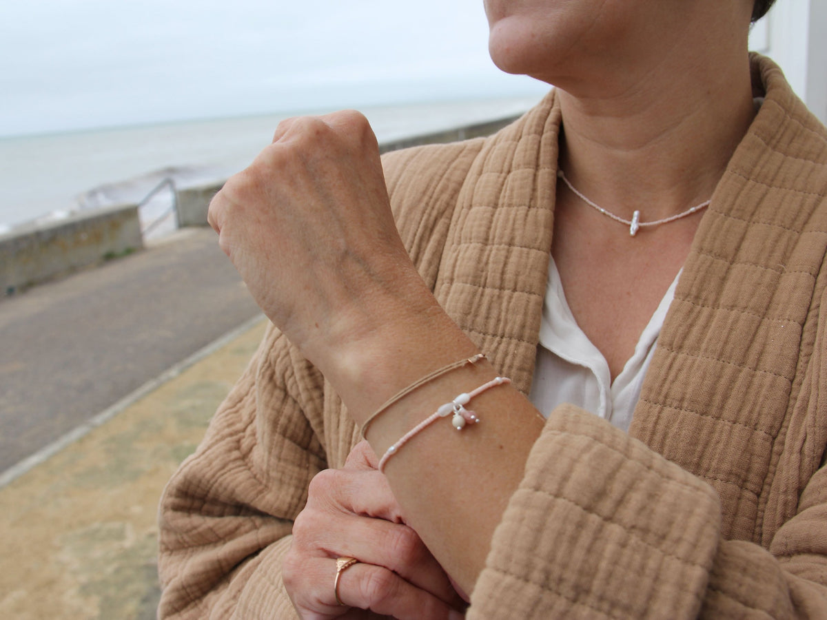 Collier Dune porté au bord de la mer avec le bracelet assorti, tons rose poudré et nacre