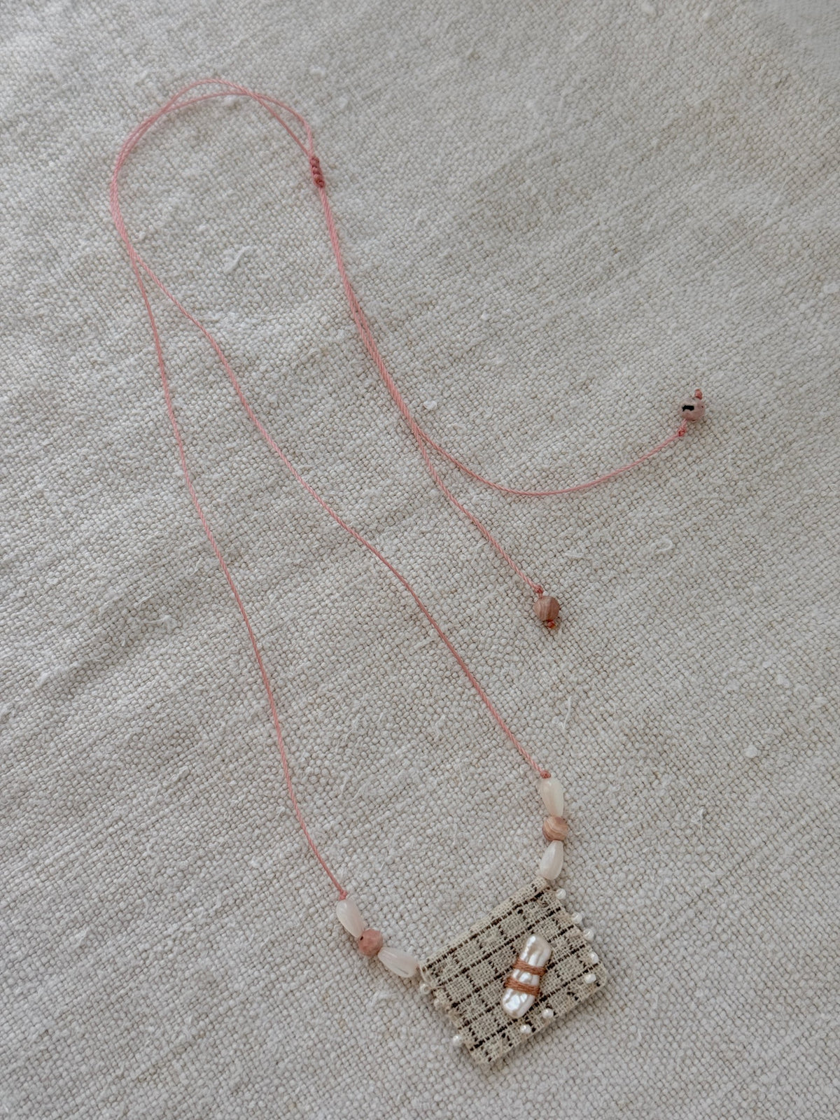 Collier long Dune en entier, cordon rose réglable et médaille en tissu à carreaux brodée de perles
