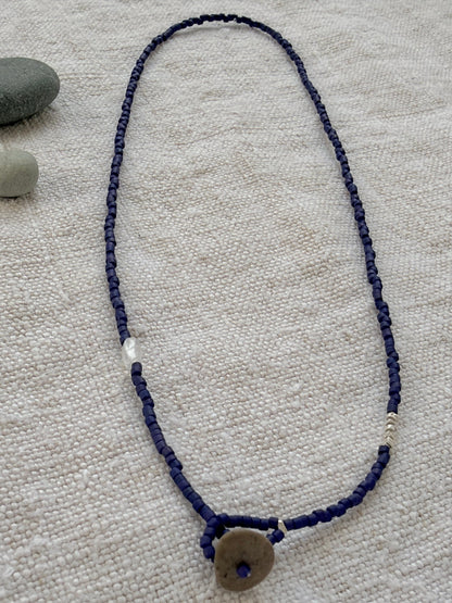 Collier lasso Embrun en perles indigo mat, fermé par un galet de plage — fait main en Normandie