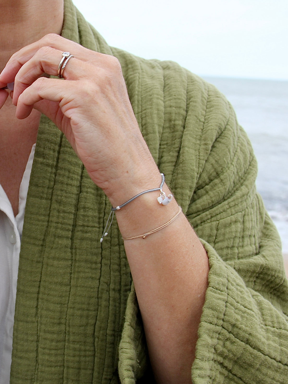 Bracelet Jour de Pluie porté au bord de la mer, perles grises et breloques pierre de lune et calcédoine