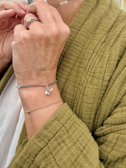 Bracelet Jour de Pluie porté avec une veste vert olive, perles gris transparent — fait main en Normandie