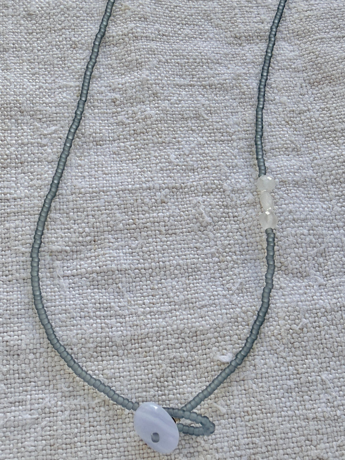 Détail du collier Jour de Pluie : calcédoine bleu-gris qui ferme le lasso et pierres de lune facettées