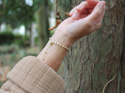 Bracelet Lichen porté contre un arbre, nacres olive nouées une à une — fait main en Normandie