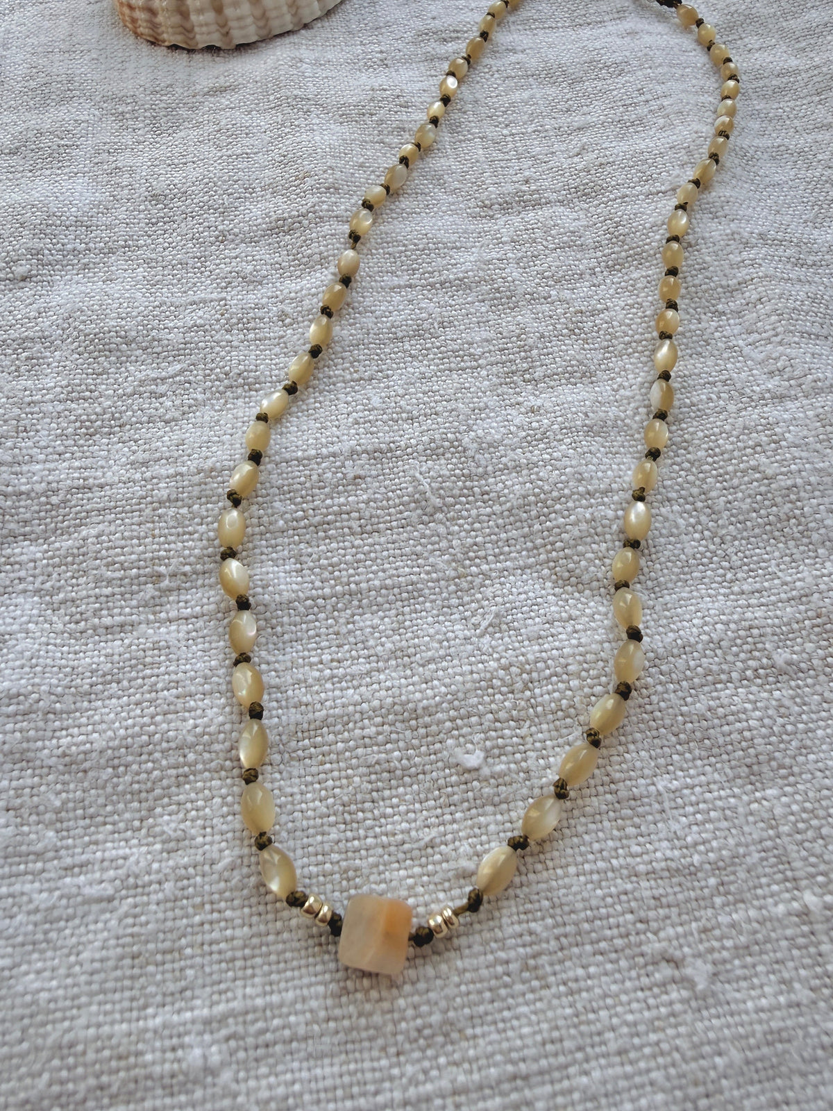 Collier Lichen en nacre olive posé sur du lin, bijou fait main en Normandie