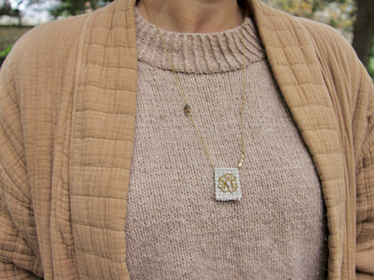Médaille brodée main du collier Lichen portée, fleur dorée sur tissu à carreaux