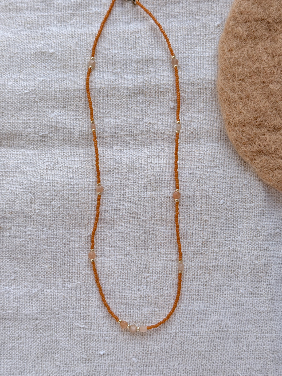 Collier court Tarte aux Pommes, perles orange cuit et pierres de lune pêche, posé sur du lin — fait main en Normandie