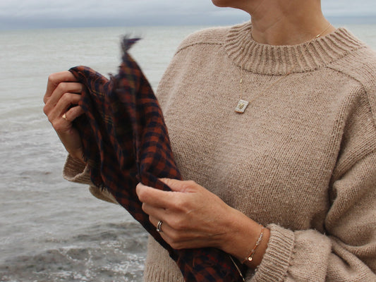 Collier long brodé Tarte aux Pommes porté au bord de la mer, médaille en tissu brodée de perles dorées