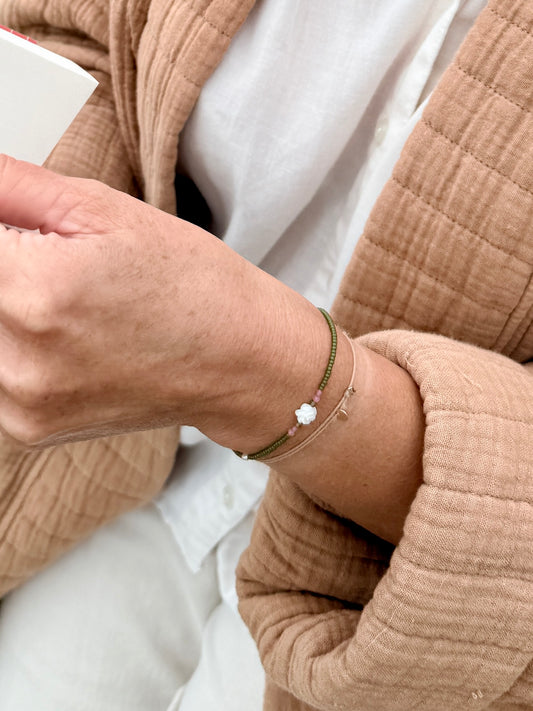 Gros plan sur le bracelet Veules porté, fleur de nacre et tourmalines roses sur perles vert avocat